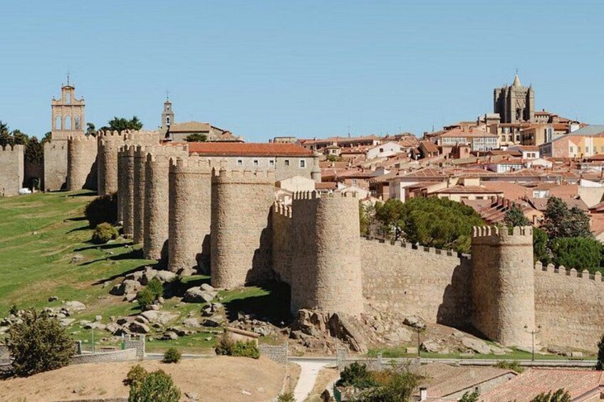 A historic stone wall with towers, a church, and a town in the background. 5
