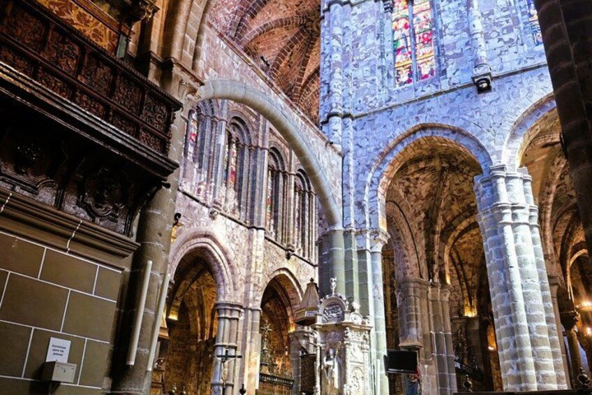 An interior of a cathedral with arched ceilings, stained glass windows, and stone columns. 4