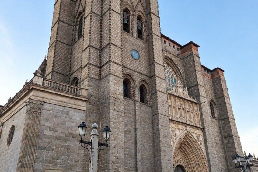 A large stone cathedral with a tall bell tower, arched windows, and a clock. 3