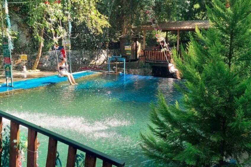 A water park with a pool, swings, and a wooden structure. 3