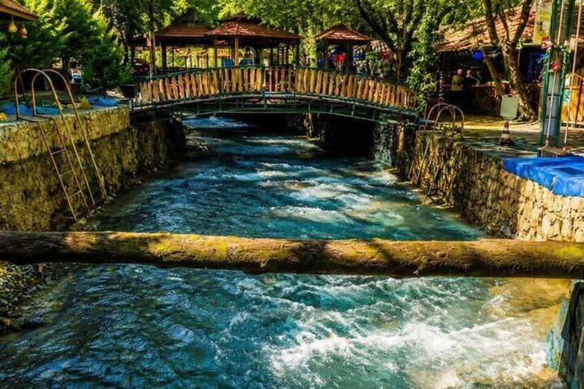 A river with a wooden bridge, stone walls, and a gazebo. 5