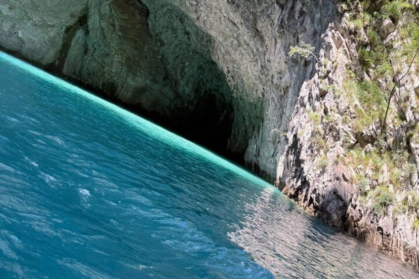 A coastal cliff with a turquoise sea and a rocky overhang. 4