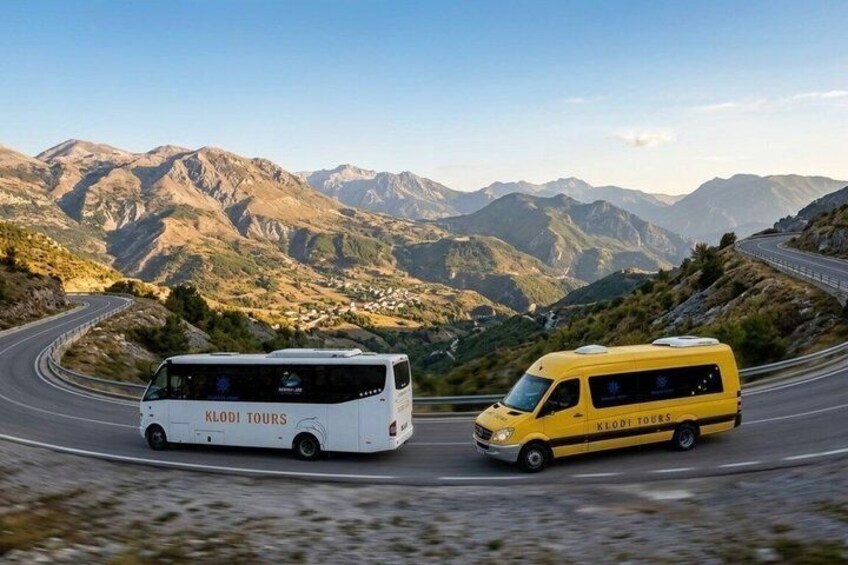 Two vehicles on a winding mountain road with a mountainous landscape in the background. 5