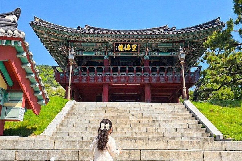 A traditional Korean building with a red and green roof, a staircase leading up to it, and a sign with Korean characters. 2