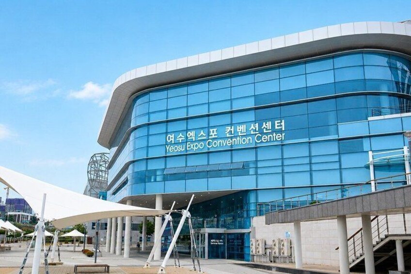 A modern building with a curved facade and large glass windows, labeled as Yeosu Expo Convention Center. 2