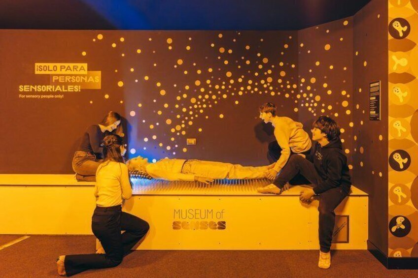 A museum exhibit with a piano and people interacting with it. 5