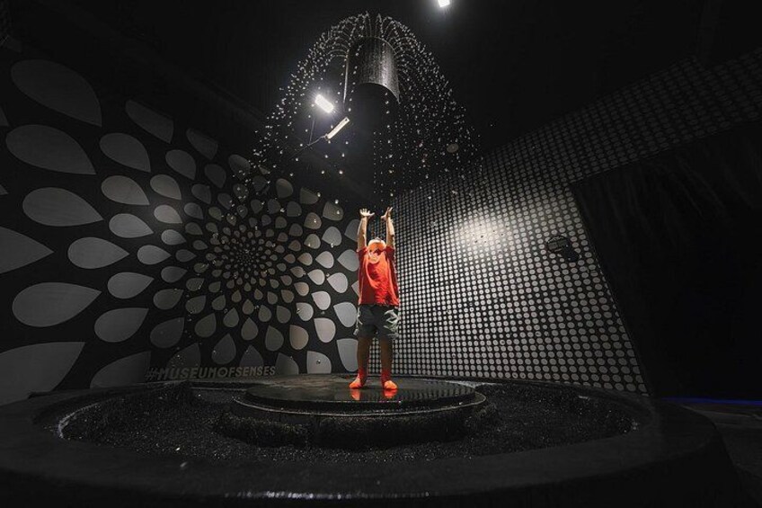 A person standing on a circular platform with a water fountain in the background. 2