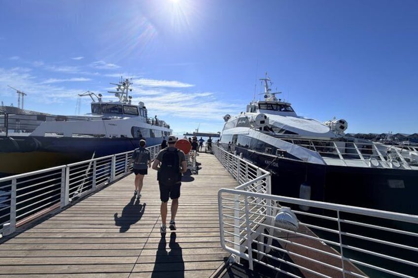 A wooden pier with two boats docked, a clear sky, and a person walking. 3