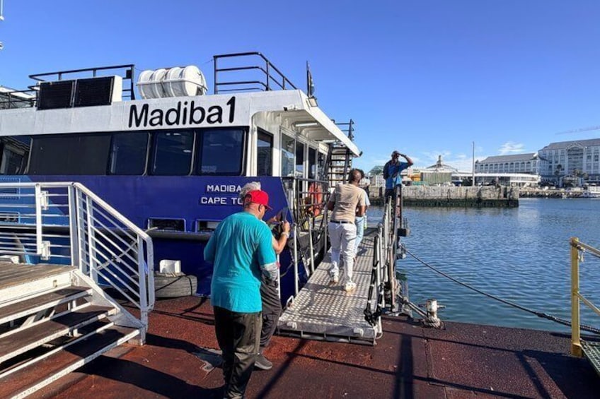 A ferry named Madiba1 docked at a port with people boarding and disembarking. 4
