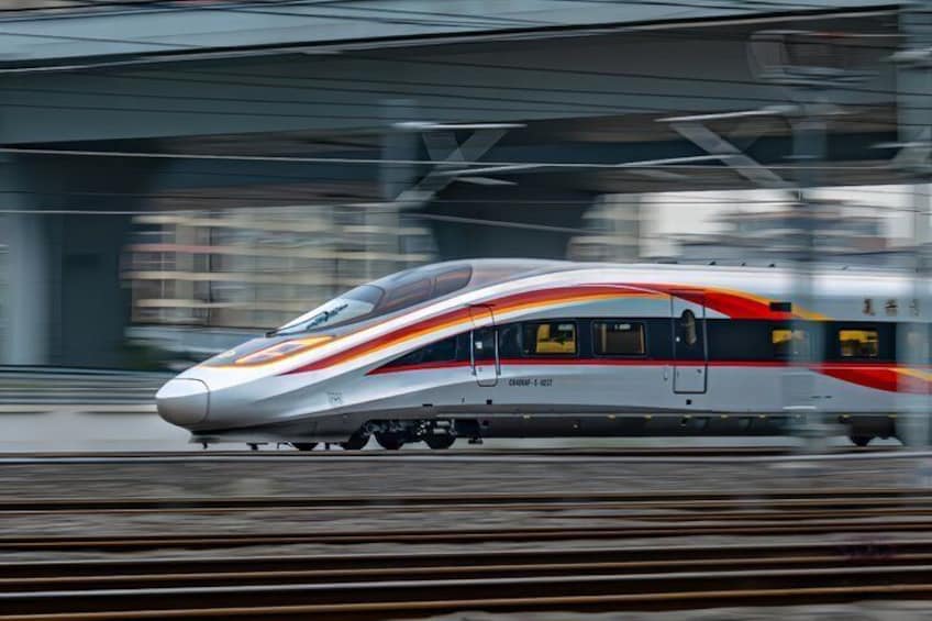 A high-speed train in motion, with a streamlined design and a color scheme of white, red, and gray. 3
