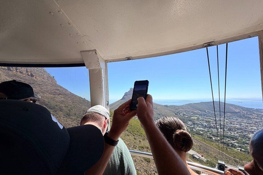 A person taking a photo with a smartphone, overlooking a mountainous landscape with a clear sky. 3
