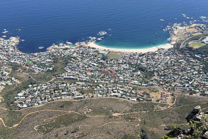 An aerial view of a coastal town with a beach, residential areas, and a hilly landscape. 2