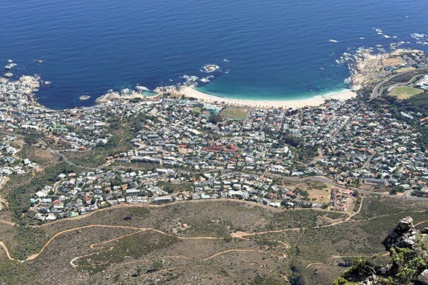 An aerial view of a coastal town with a beach, residential area, and surrounding hills. 2