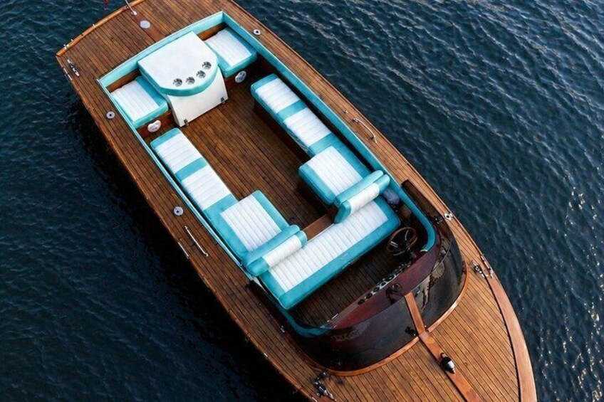 A wooden boat with a cabin, seating, and a motor. 1