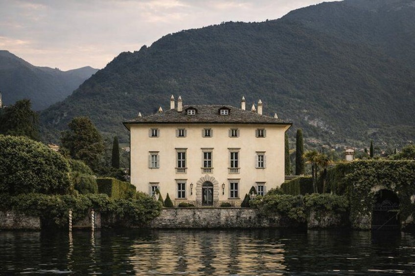 A large, white building with a symmetrical facade, surrounded by water and mountains. 5