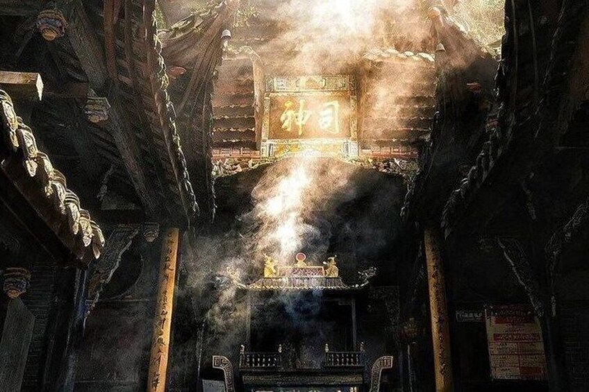 A traditional Chinese temple with incense burning, ancient architecture, and a sign with Chinese characters. 3