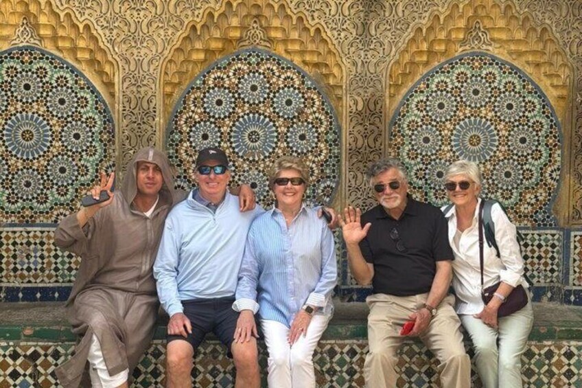 A group of people seated in front of ornate, circular patterned wall designs. 1