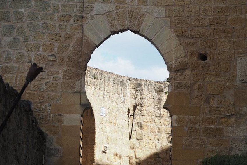 An arched stone doorway with a weathered wall and a metal object leaning against it. 2