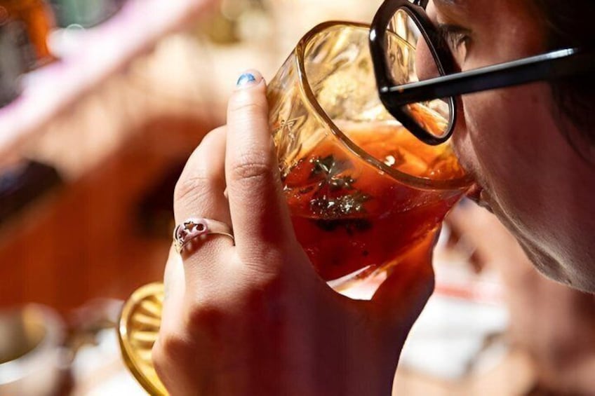 A person holding a glass with a drink, wearing a ring, and glasses. 1