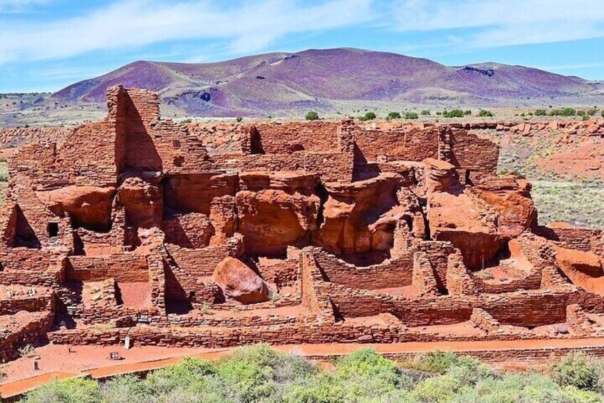Ancient red-brick ruins in a desert landscape with distant mountains. 4