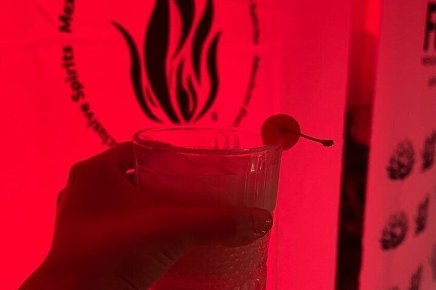 A hand holding a clear glass with a cherry garnish. 2
