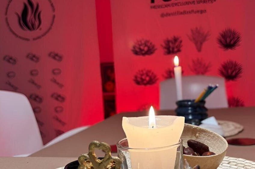 A table with a lit candle, a glass of a light-colored beverage, and decorative items. 1