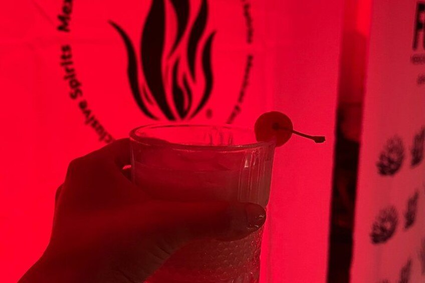 A hand holding a clear glass with a cherry garnish. 2