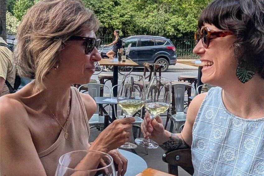 Two people sitting at an outdoor table, holding wine glasses. 1