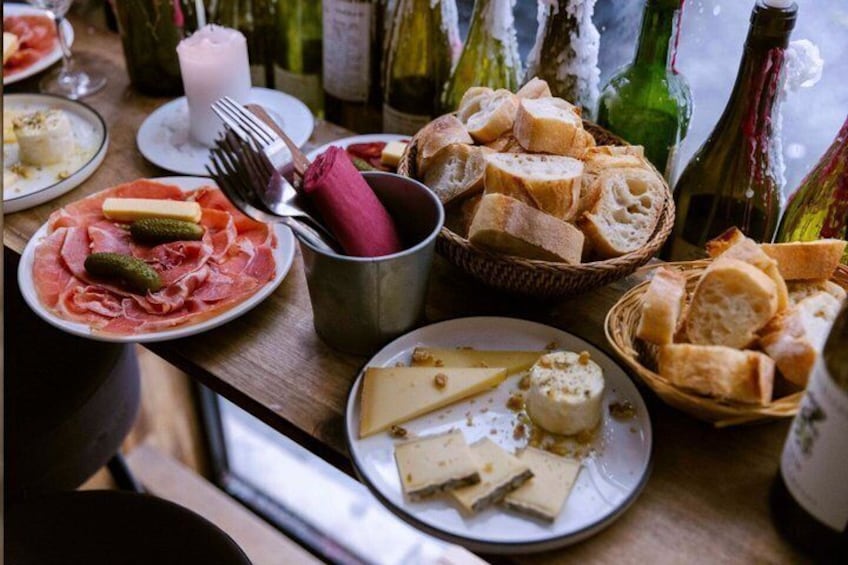 A table with plates of food, bread, and wine bottles. 5