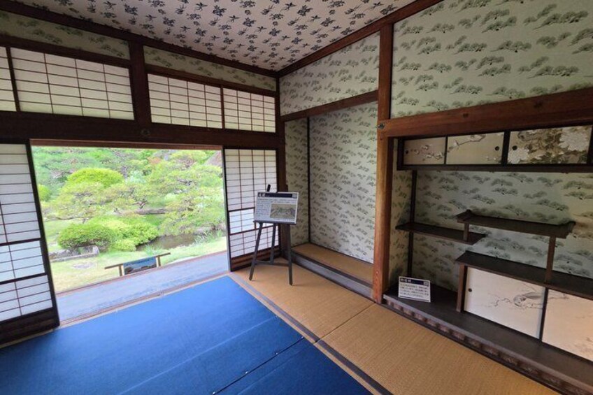 A traditional Japanese room with tatami flooring, shoji screens, and a view of a garden. 5