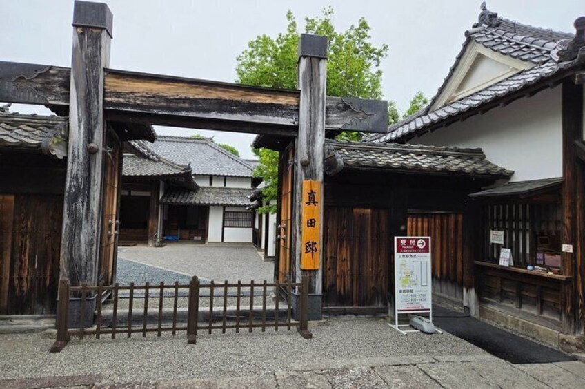 A traditional Japanese gate with wooden pillars and a signboard. 2