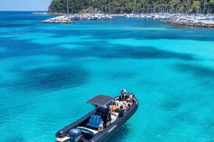 A boat on turquoise water with a rocky island in the background. 3