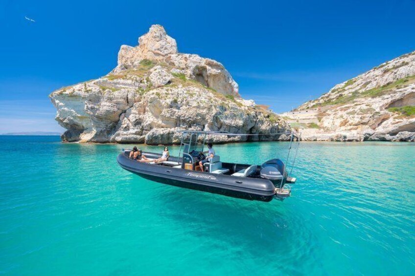 A boat on turquoise water with rocky cliffs in the background. 4
