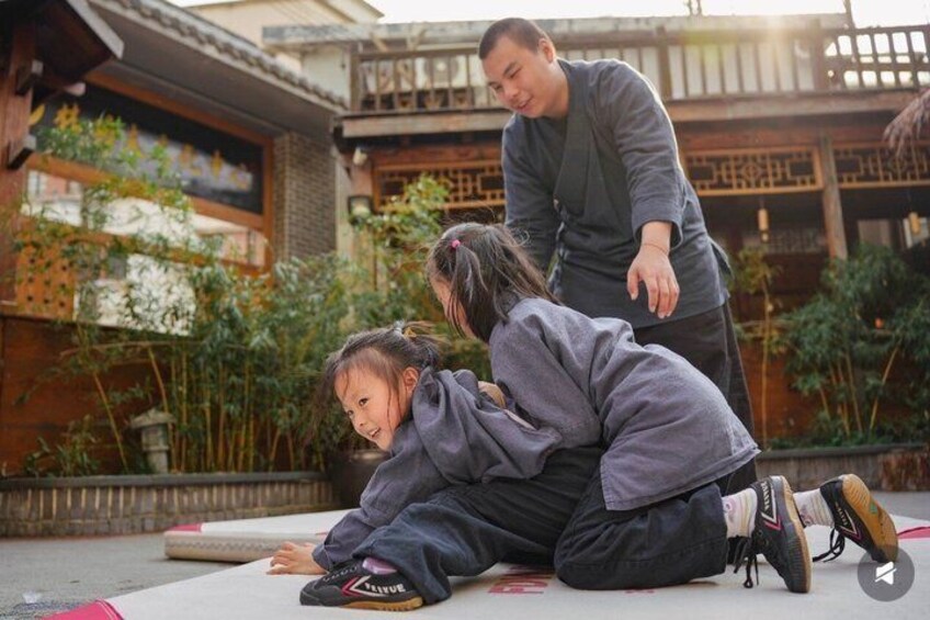 Two children playing on a mat in a courtyard with traditional architecture. 5