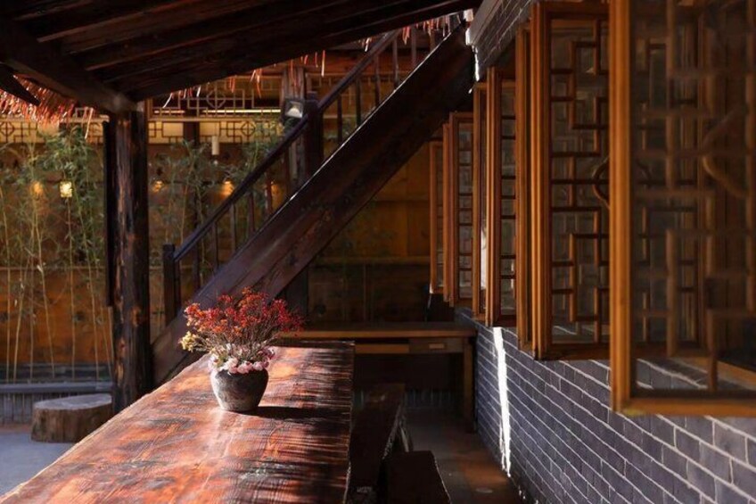 A wooden staircase leading to a room with a brick wall and a potted plant with red flowers. 3