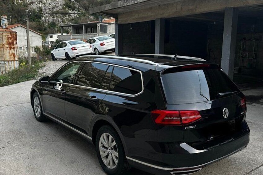 A black Volkswagen Passat parked in a driveway with a garage in the background. 3