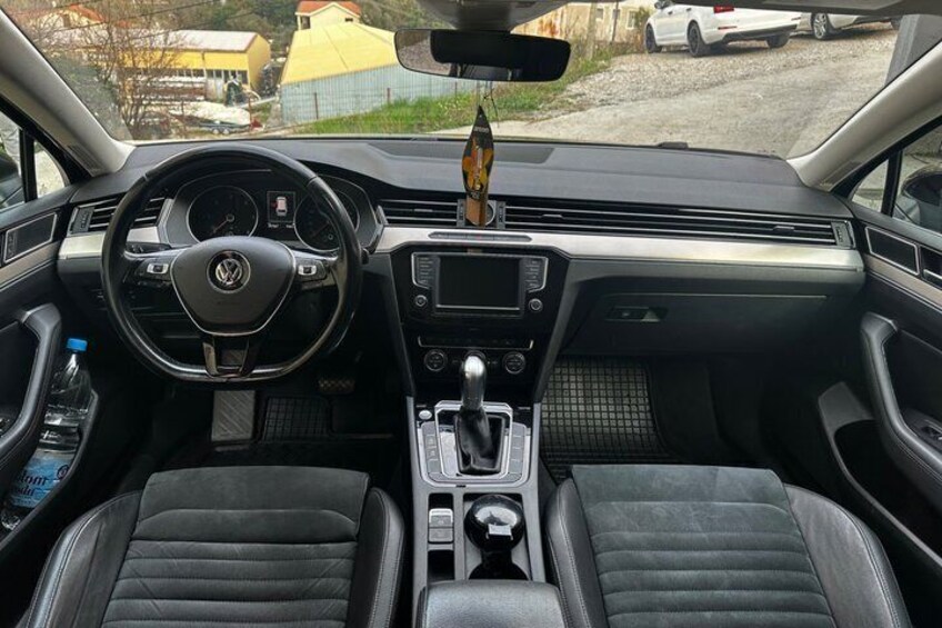 A car interior with a steering wheel, dashboard, and two front seats. 2