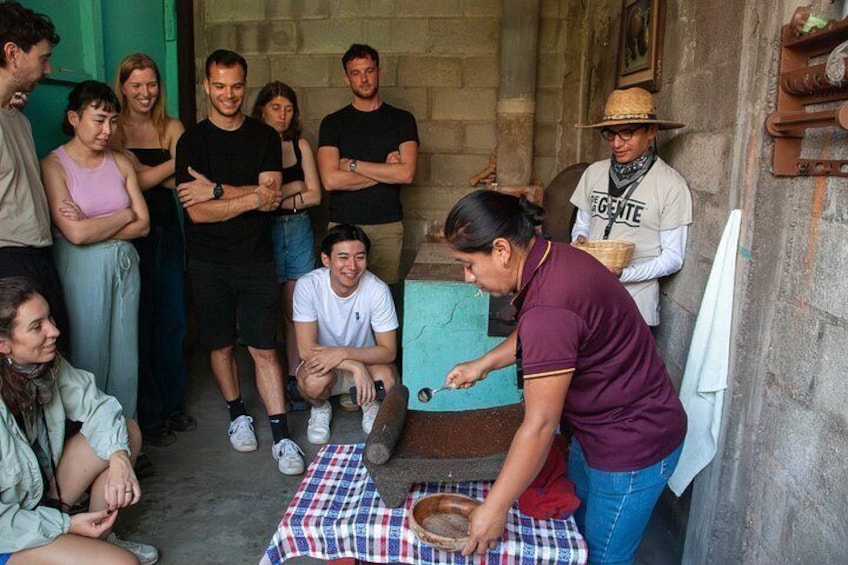 A group of people gathered around a cooking activity with a person preparing food on a table. 4
