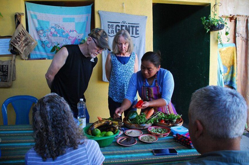 A group of people preparing food at a table with various vegetables and dishes. 2