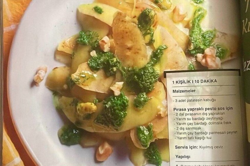 A plate of food with potatoes, broccoli, and nuts, and a menu listing ingredients. 2