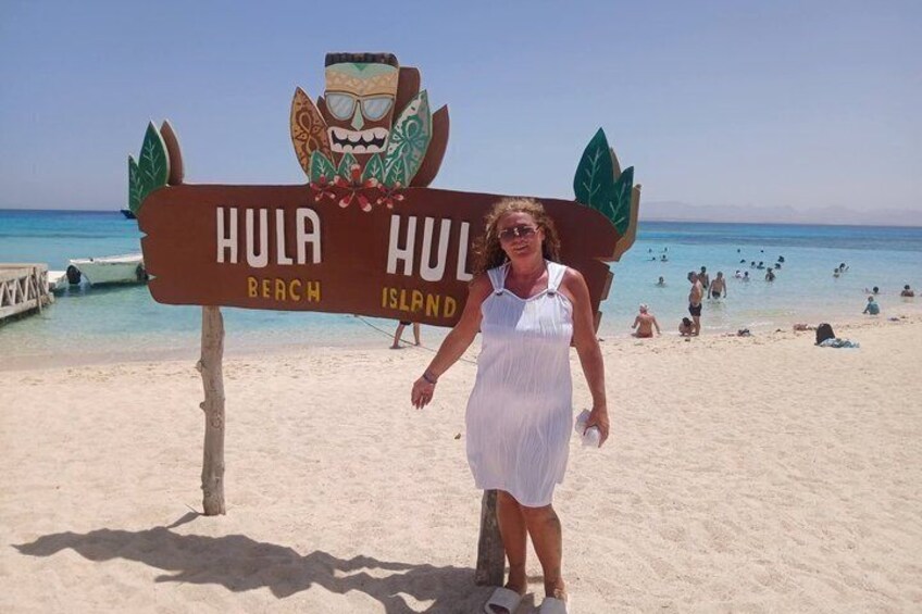 A beach sign with a tropical design, a sandy beach, and the ocean in the background. 4