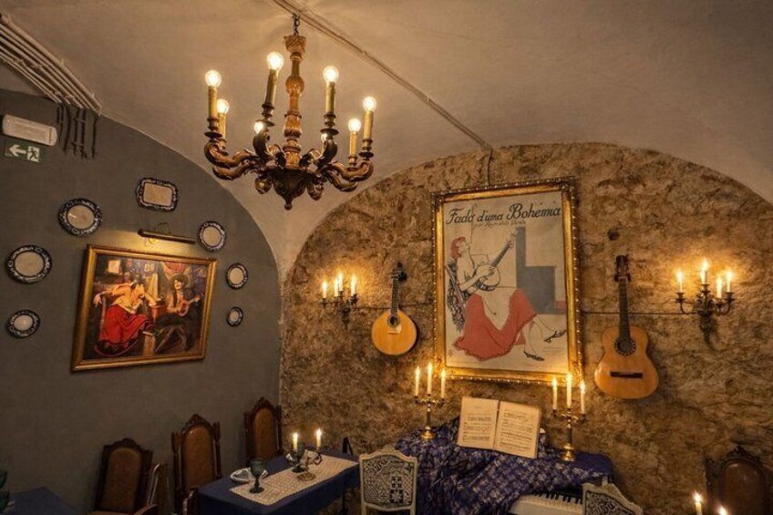 A restaurant interior with a stone wall, a chandelier, guitars, and a poster. 1