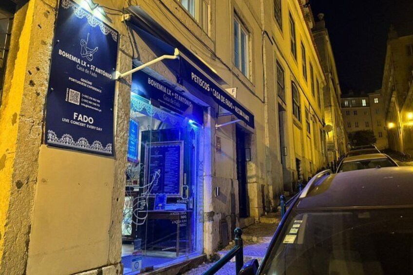 A nighttime street scene with a building displaying 'BOHEMIA LX' and 'FADO' signs, and a parked car. 5