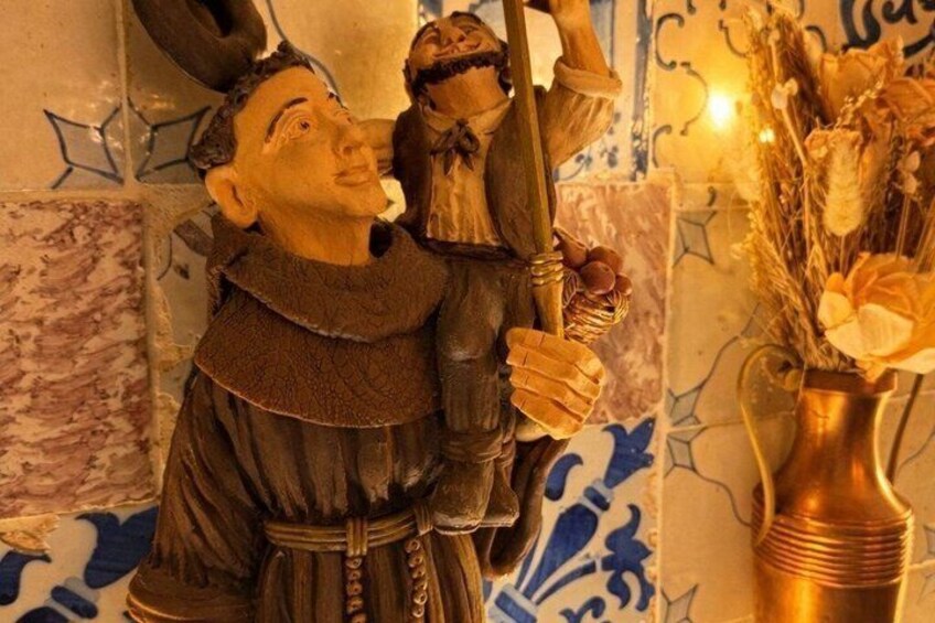A statue of a man with a staff, a vase with dried flowers, and a tiled wall with blue patterns. 2