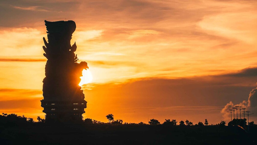 A tall, ancient structure silhouetted against a sunset sky. 1