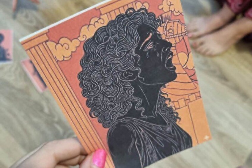 A person holding a card with a black and white illustration of a woman with curly hair. 3
