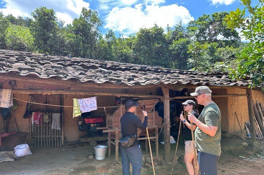 A rustic wooden structure with a tiled roof, a person holding a camera, and another person standing nearby. 5