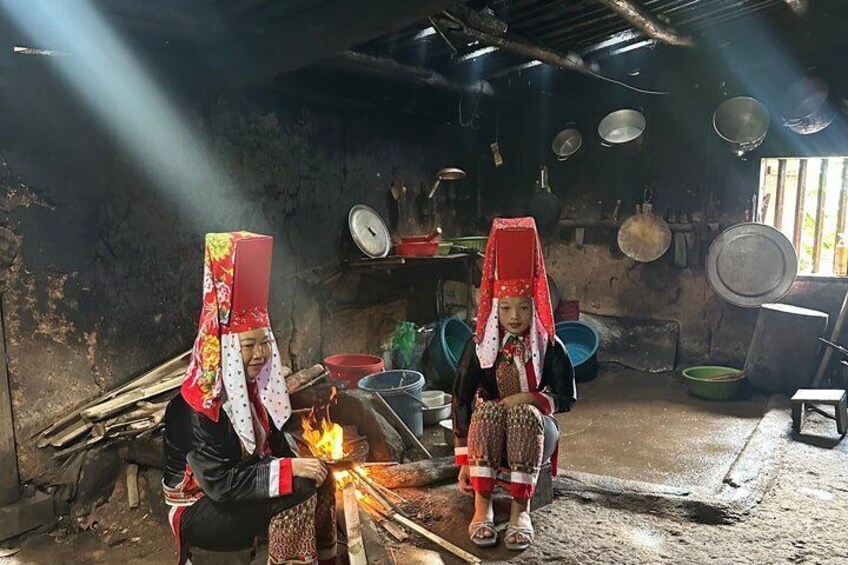 Two individuals in a rustic kitchen with cooking fire, cookware, and a traditional hut. 2