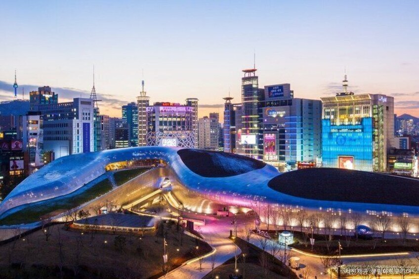 A cityscape with illuminated buildings and a large, uniquely shaped stadium. 2
