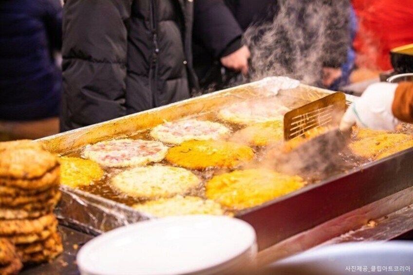 A street food vendor cooking patties in a large pan. 4